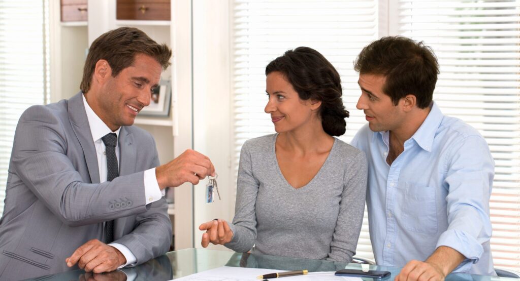 Couple receiving house keys from estate agent on completion day in the UK