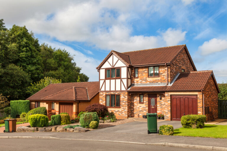 Traditional British detached house with garden, garage, and red brick exterior.