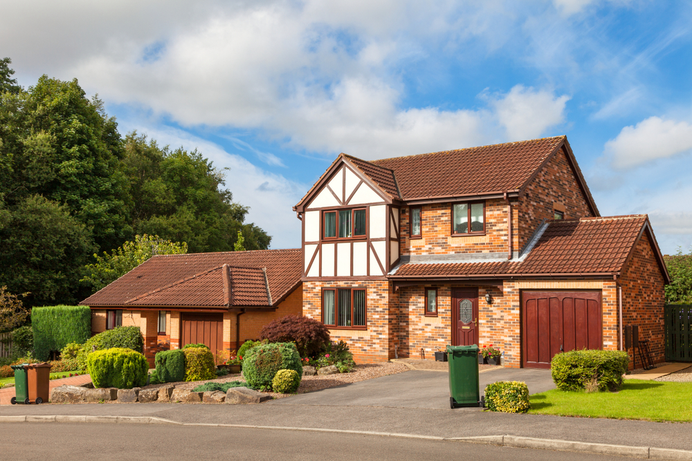 Traditional British detached house with garden, garage, and red brick exterior.