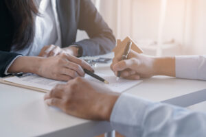 Client signing property agreement with estate agent at desk.