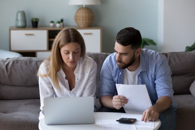Couple reviewing finances together with laptop, papers and calculator