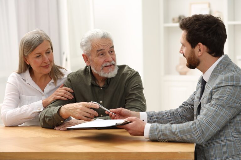 Elderly couple discussing documents with advisor at a table.