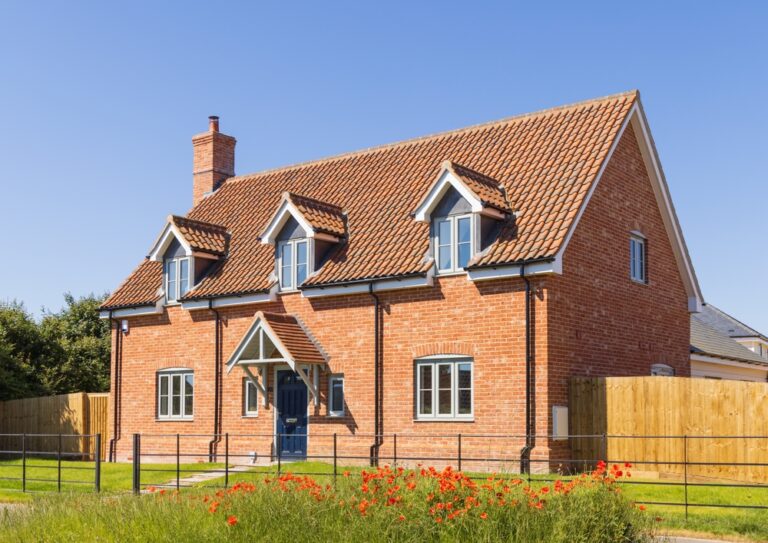 Modern red brick detached house with dormer windows and front garden