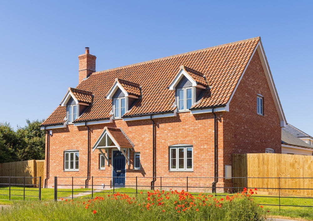 Modern red brick detached house with dormer windows and front garden