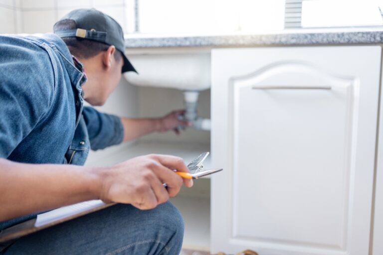 Home inspector checking plumbing under kitchen sink