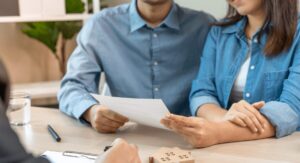 Couple reviewing rental contract with estate agent at desk