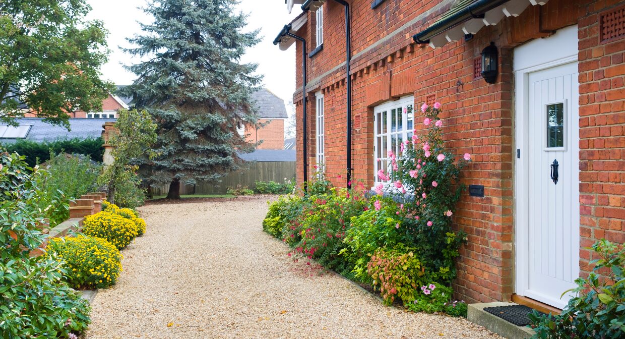 Front view of a traditional brick UK house with a neat gravel driveway and tidy garden, representing Whitegates’ autumn 2025 selling strategies.