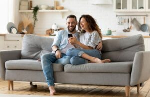 Couple sitting on a couch, looking at a phone.