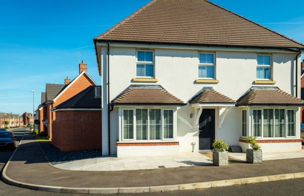 Two-story house with large windows and landscaped entrance.