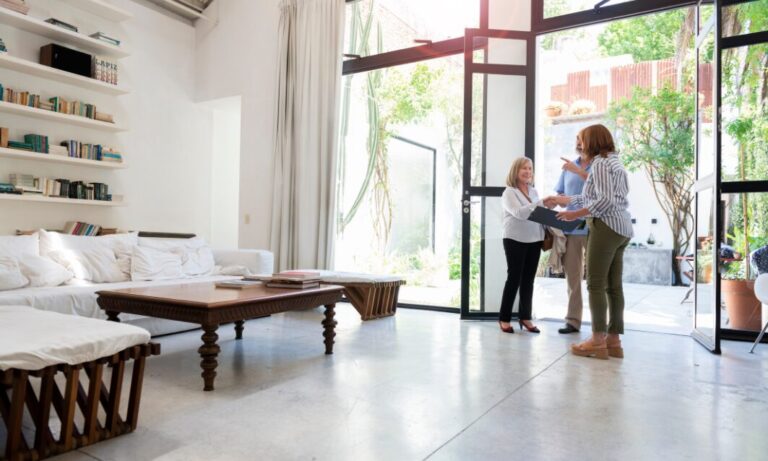 Letting agent welcoming a couple into a bright modern home during a property viewing.