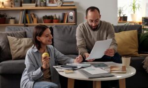 Couple sitting at a table reviewing documents and budgeting together in their living room.