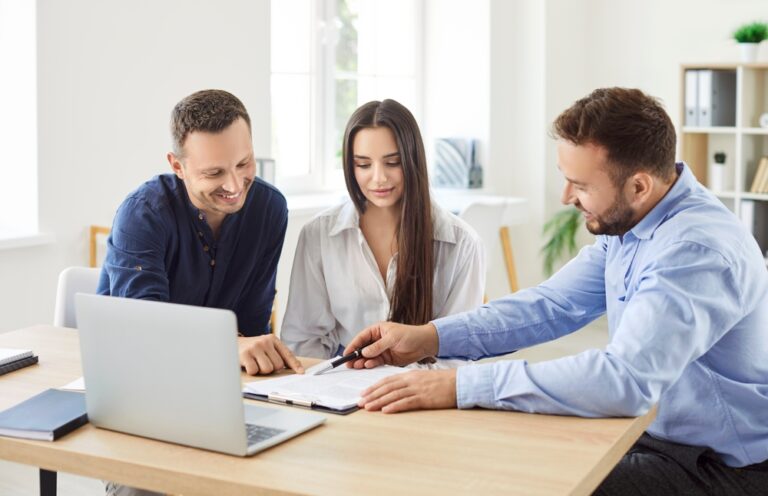 Couple reviewing documents with an adviser at a desk in a bright office