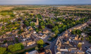 Aerial view of a UK market town with residential streets, green spaces and a church at the centre, showing surrounding homes and countryside