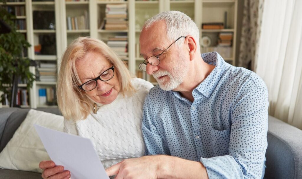 Older couple sitting on a sofa in their Huddersfield home reviewing property documents and discussing housing decisions for 2026.