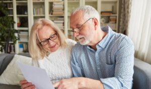 Older couple sitting on a sofa in their Huddersfield home reviewing property documents and discussing housing decisions for 2026.