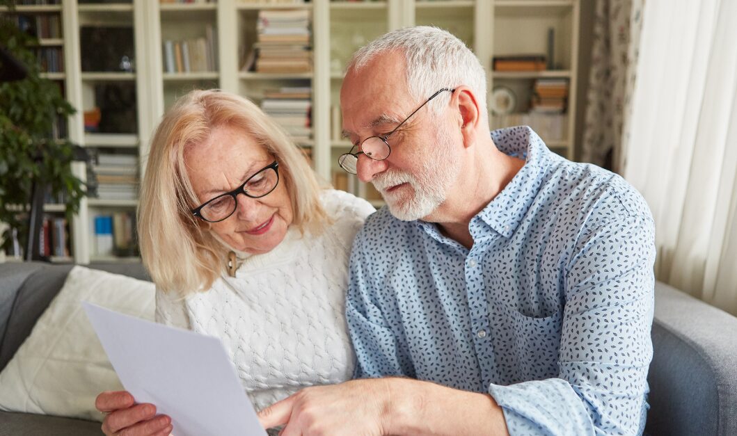 Older couple sitting on a sofa in their Huddersfield home reviewing property documents and discussing housing decisions for 2026.