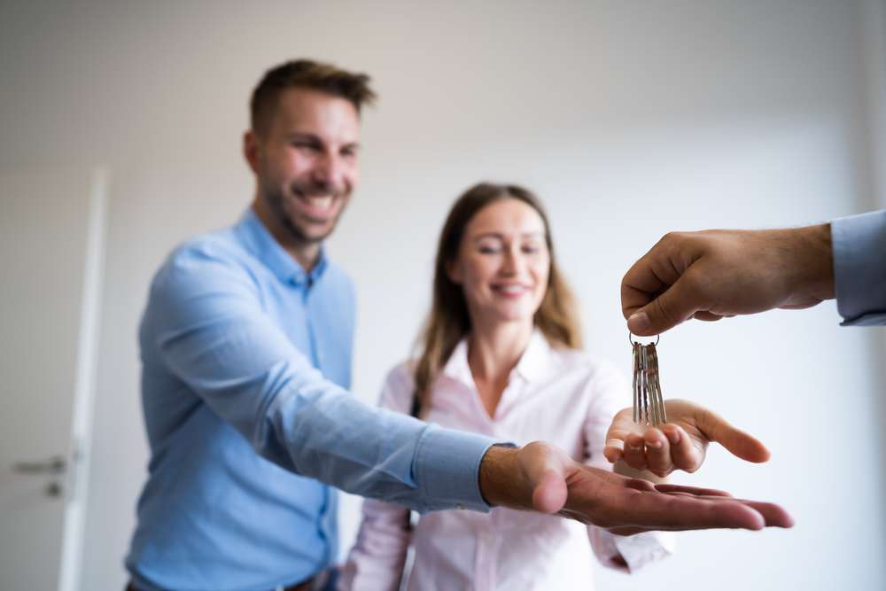 Estate agent handing over house keys to happy couple