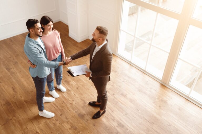 Estate agent shaking hands with couple during property viewing