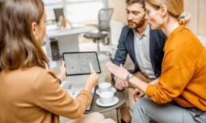 Estate agent showing property layout on tablet to couple, representing regeneration impact on house valuation in Pontefract