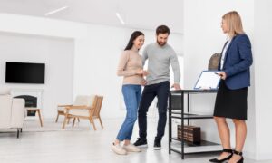 Estate agent discussing rental property details with tenants in a modern home related to the decent homes standard private rental rules.