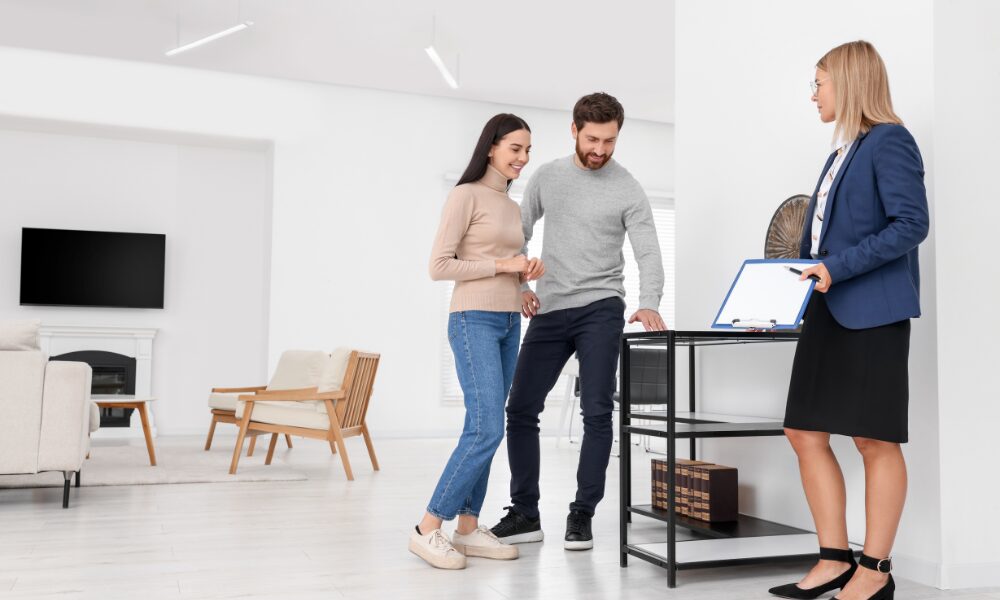 Estate agent discussing rental property details with tenants in a modern home related to the decent homes standard private rental rules.