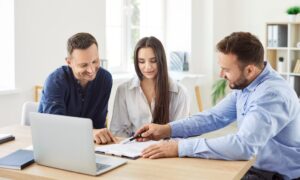 Estate agent explaining rental paperwork to couple at table, representing professional property management in West Derby