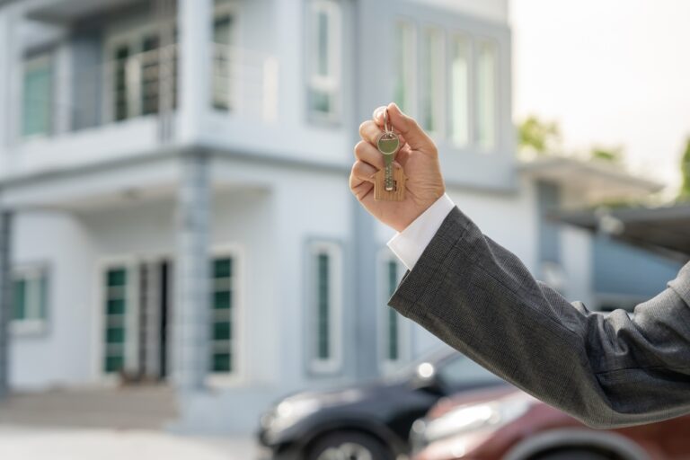 Real estate agent holding house keys in front of a modern home