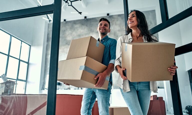 Young couple carrying boxes into their new home, first-time buyers