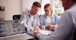 Young couple signing tenancy paperwork with a letting agent in Walton Vale property office.