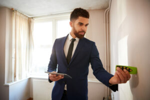 Property surveyor inspecting walls inside a residential property