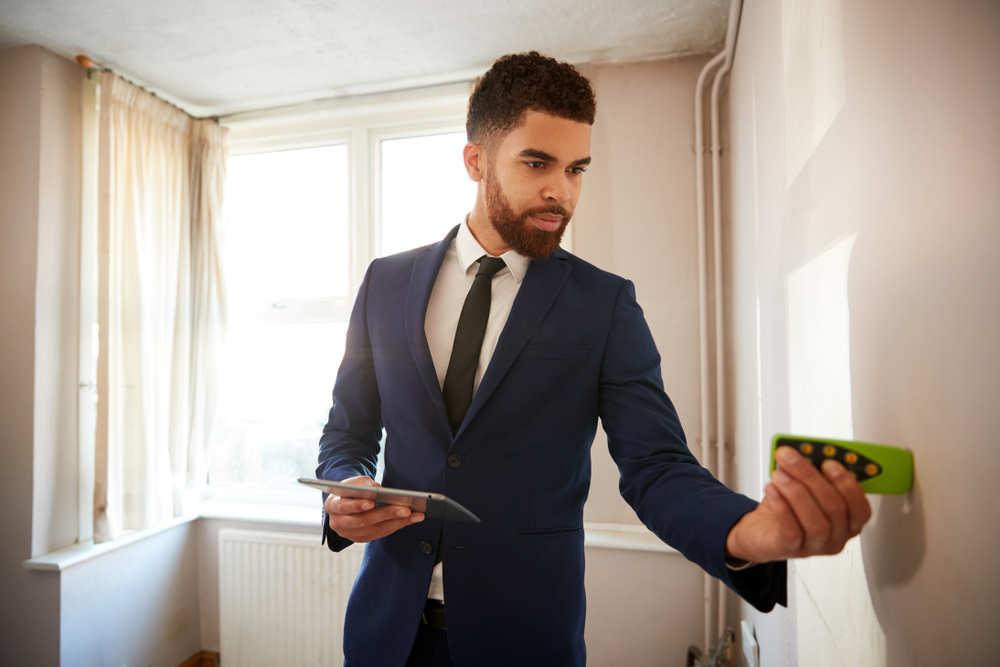 Property surveyor inspecting walls inside a residential property