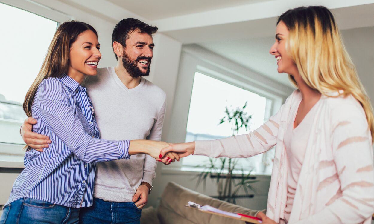 A property agent shaking hands with a smiling couple during a home viewing, representing buyers and renters exploring property options while living in Pontefract WF8.