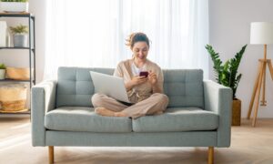 A tenant relaxing at home while using a laptop and smartphone to search for rental properties in Huyton.