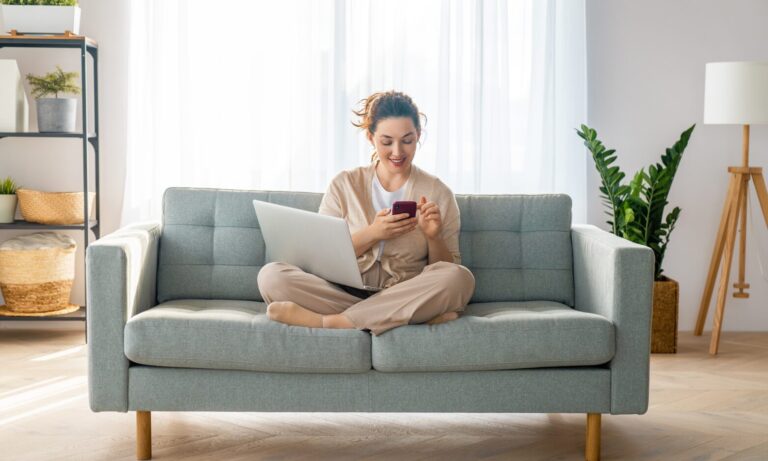 A tenant relaxing at home while using a laptop and smartphone to search for rental properties in Huyton.