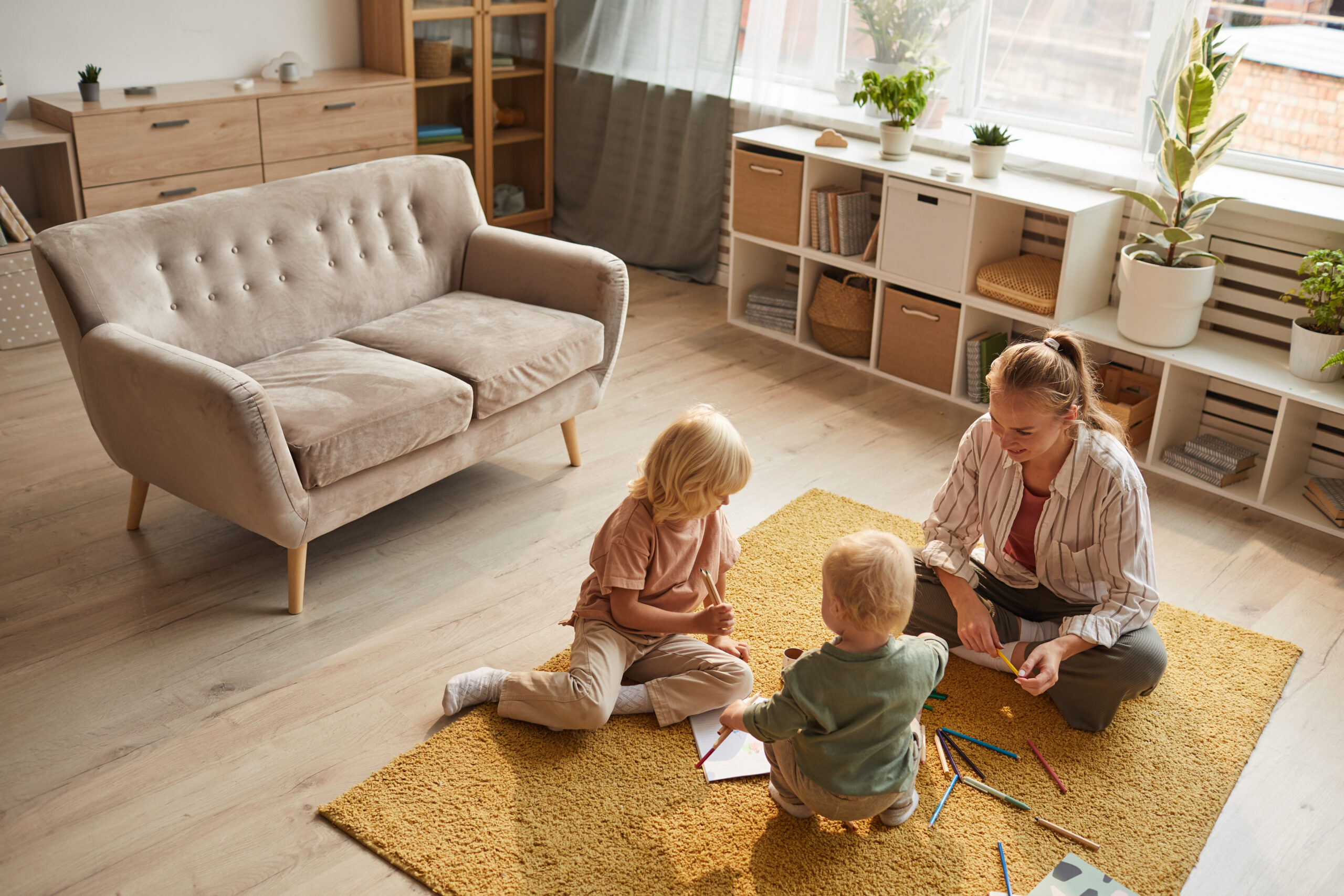 A mother and two children enjoying time together in a bright family living room, representing family life in Old Swan (L13).
