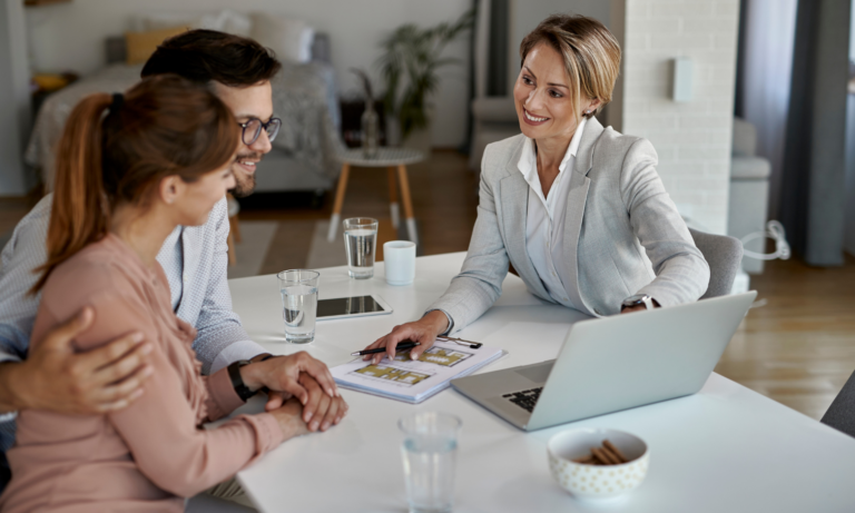 First-time buyers discussing a property purchase with an estate agent during a home consultation.