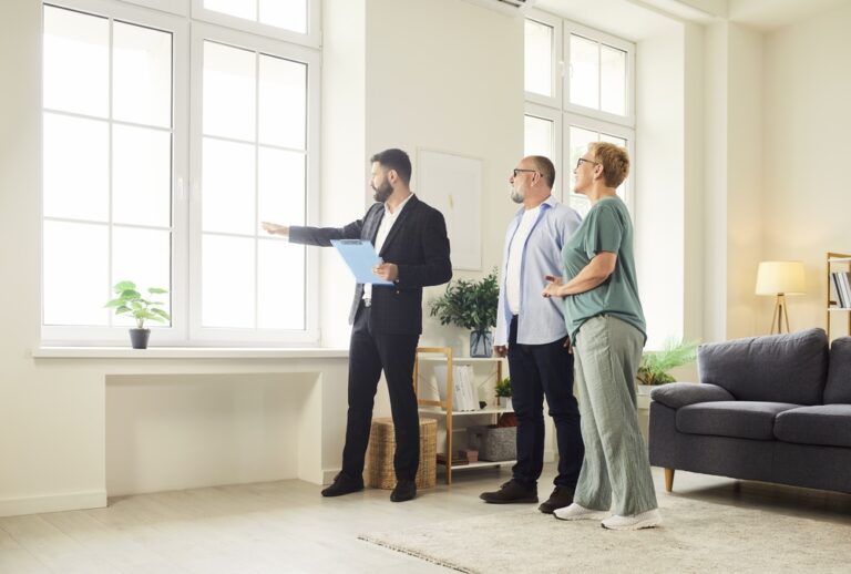 Estate agent showing a bright living room to a couple during a property viewing