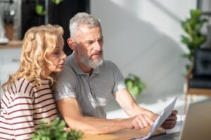 Couple reviewing property documents at home with a laptop