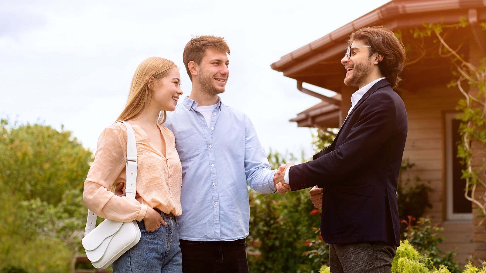 Estate agent shaking hands with homeowners outside a residential building in Prescot, L34